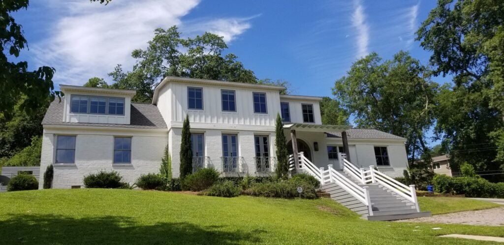A large white home with a blue sunny sky in the background.
